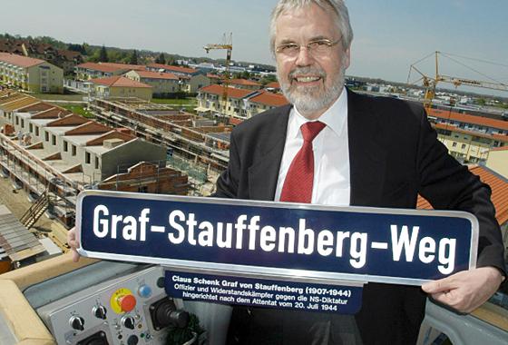 Seit 2005 gibt es in Ismaning den Graf-Stauffenberg-Weg. Bürgermeister Michael Seldmair präsentiert das Schild mit der neuen Ergänzung. Foto: Ulla Baumgart