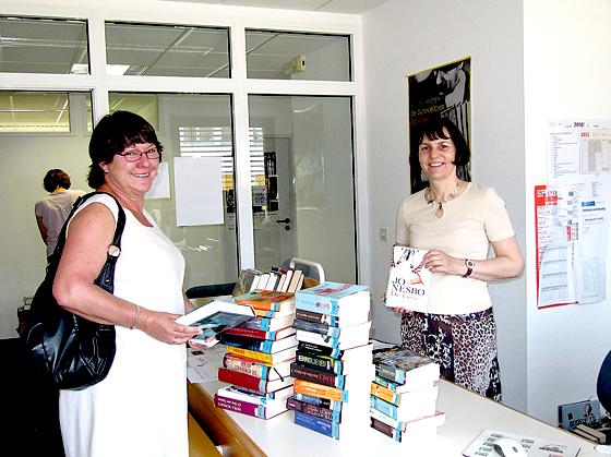 Daniela Heim vom Bücherei-Team (r.) rät den Nutzern sich mit reichlich Lesestoff bis zur Wiedereröffnung im Oktober einzudecken.	Foto: Woschée