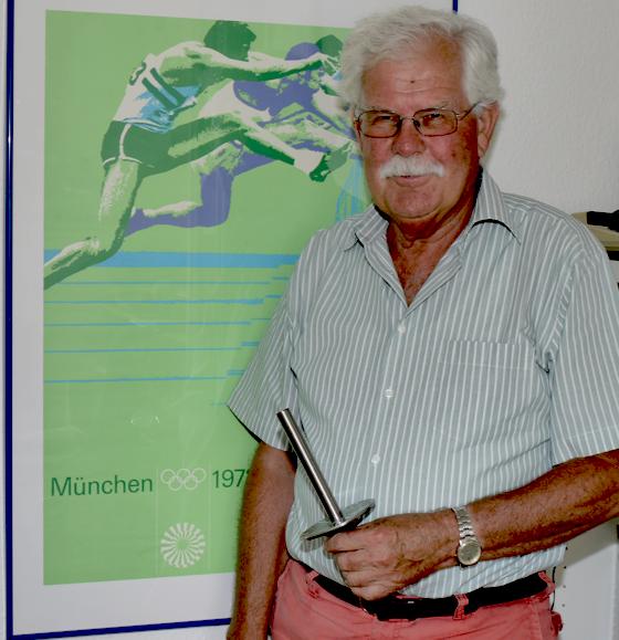 TSV-Präsident Volker Panzer mit der Fackelkopie, die alle Läufer als Andenken erhielten. Im Hintergrund ein Original-Plakat der Olympischen Spiele 1972. Foto: Kohnke