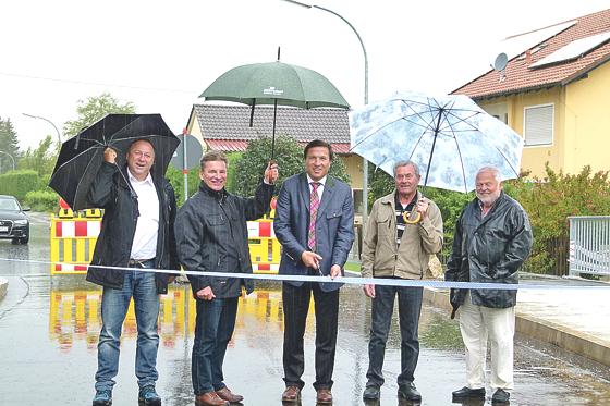 Mit einem Schnitt durch das weiß-blaue Band gab Bürgermeister Max Gotz (Mitte) bei strömendem Regen die Semptbrücke in Eichenkofen wieder für den Verkehr frei. 	Foto: bb