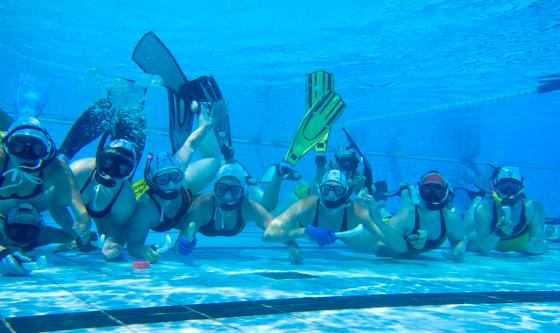 Die Münchner Unterwasserhockey-Spielerinnen mit ihrem Sportgerät, dem Stick, und Bleipuck (rot).	Foto: Verein