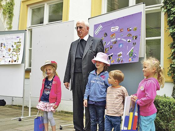 Weihbischof Engelbert Siebler mit den Kindern des Kindergartens Mintraching vor ihrer Collage. Foto: VA