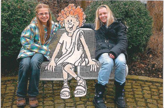 Theresa (li.) und Alisia sitzen mit dem Römerjungen Felix auf einer Bank und betrachten Ottobrunn. 	Fotocollage: Alisia Beckmann / Theresa Ulbricht