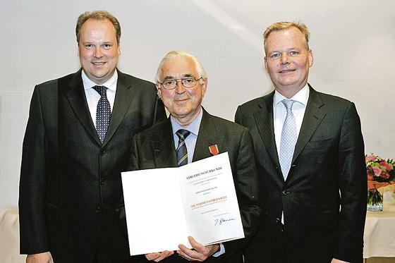 Landrat Christoph Göbel, Wolfgang Kuny und Bürgermeister Jan Neusiedl (v. l.) bei der Übergabe der Bundesverdienstmedaille.	Foto: VA
