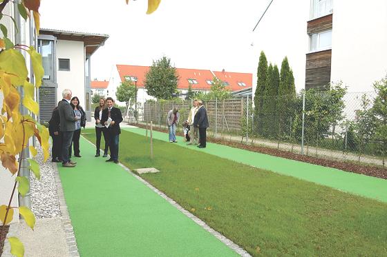 Bürgermeister Andreas Kemmelmeyer (Mitte) den neuen, unproblematisch begehbaren Kunststoffweg des Dementengartens.	Foto: Gemeinde