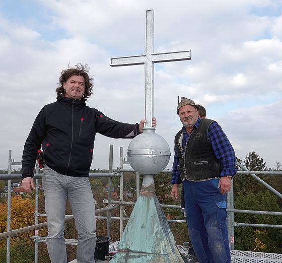 Zimmermeister Jörg Schwarz (li.) und Dachdeckermeister Johann Rauch setzten das gefüllte Kirchturmkreuz wieder ein.	Foto: privat