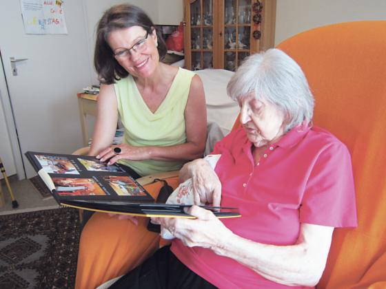 Eine ehrenamtliche Helferin betrachtet mit einer Seniorin ein Fotoalbum. Foto: Stephan Zöller/BW