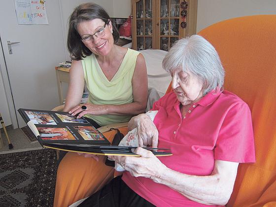 Eine ehrenamtliche Helferin betrachtet mit einer  Seniorin Familienbilder.	Foto: Stephan Zöller / MBW