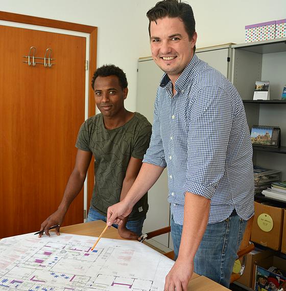 Rathausmitarbeiter Adrian Okrey (r.) studiert mit seinem Praktikanten Berhane Teklay einen Bauplan.	Foto: MO