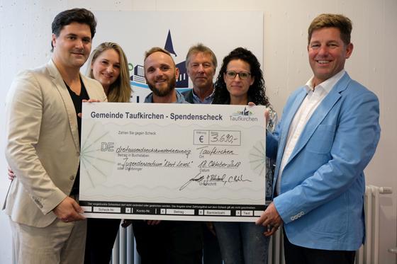 Pfarrer Rohrbach und seine Band übergaben an Bürgermeister Ullrich Sander einen Spendenscheck in Höhe von 3.690 Euro für die Jugendarbeit. Foto: VA