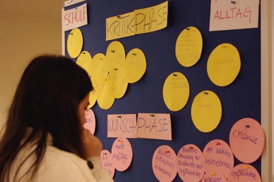 Eine Teilnehmerin vor einer Pinnwand mit Ideen, die im Demokratie-Workshop entstanden sind. Foto: mehrWERT Demokratie
