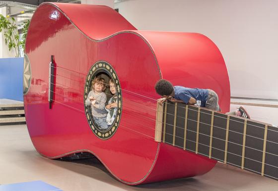 Das Kinderreich im Deutschen Museum: In der roten Riesengitarre kann man erleben, wie es sich anfühlt, wenn draußen jemand an den Saiten zupft. Foto: Deutsches Museum