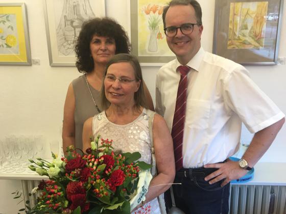 Die Künstlerin wird mit einem Blumenstrauß begrüßt. Chrissie Elsing (Mitte) mit Landtagsvizepräsident Markus Rinderspacher und Astrid Schweizer, SPD-Chefin von Ramersdorf. Foto: Privat