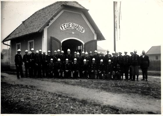 Feuerwehrleute stehen vor dem ersten Feuerwehrhaus der Feuerwehr Neubiberg beim Rathausplatz. Foto: FFW Neubiberg