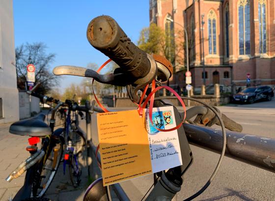 Das Gedicht „Selfie mit Mundschutz“ von Thomas Glatz hängt an einem verwaisten Radl gegenüber der Heilig-Kreuz-Kirche in Giesing. Foto: Poesieboten