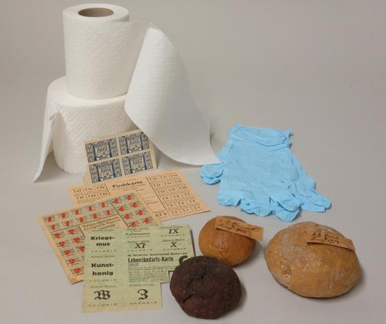 Kriegssemmeln und Lebensmittelkarten aus den Weltkriegen sowie begehrte Ware in der Corona-Krise: Toilettenpapier und Schutzhandschuhe. Foto: Museum Erding