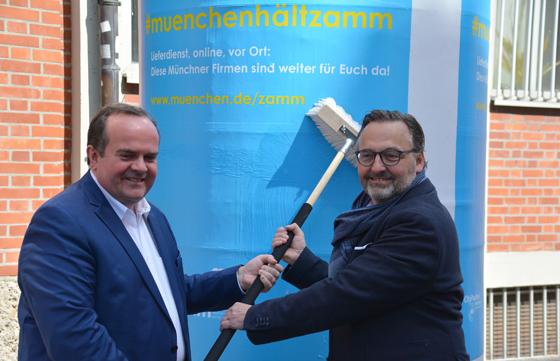Kulturreferent Anton Biebl ( rechts) bringt gemeinsam mit Clemens Baumgärtner, Referent für Arbeit und Wirtschaft, Werbeplakate für die neue Plattform "#muenchenhältzamm" in der Stadt an Litfaßsäule an. Foto: LHM/RAW