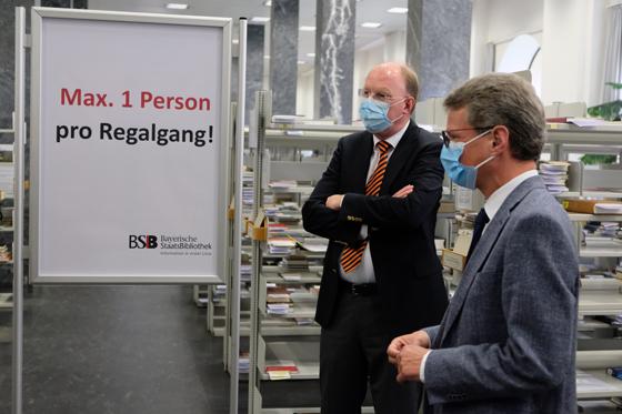 Kunst- und Wissenschaftsminister Bernd Sibler (r.) überzeugt sich zusammen mit dem Generaldirektor der Bayerischen Staatsbibliothek Dr. Klaus Ceynowa (l.) von den Hygiene- und Sicherheitsmaßnahmen bei der Ausleihe. Foto: BSB