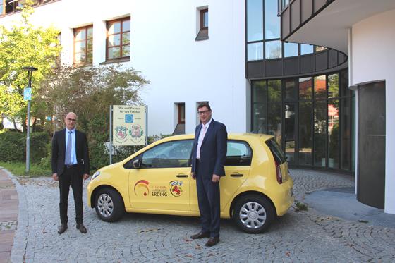 Landrat Martin Bayerstorfer und Krankenhausdirektor Dr. Dirk Last vor dem neuen sonnengelben Elektro-Dienstwagen des Klinikums Erding. Foto: LRA Erding