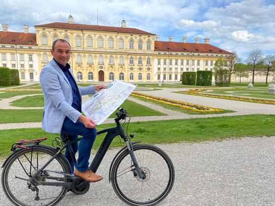 Schön radeln in Schleißheim: Bürgermeister Markus Böck präsentiert die neu aufgelegte Radwanderkarte der NordAllianz vor dem Neuen Schloss Schleißheim. Foto: Gemeinde
