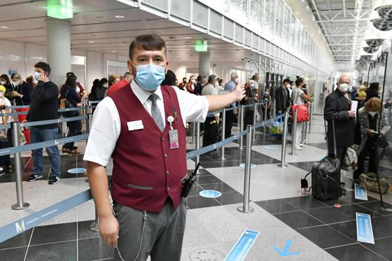 Flughafen-Mitarbeiter Hasan Aydin hilft Passagieren beim Check-in-Prozess oder bei der Passkontrolle, die notwendigen Reise-Dokumente bereit zu halten. Foto: Flughafen München