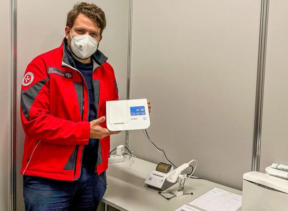 Florian Weber zeigt eines der neuen molekulardiagnostischen Testsysteme für die Testauswertung. Foto: Johanniter/Jason Podt