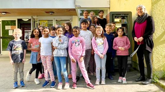 Rektorin Marion Lange freut sich gemeinsam mit einem Teil der Schüler der Grundschule an der Kafkastraße über den prall gefüllten Kinderbücherschrank. Foto: hw