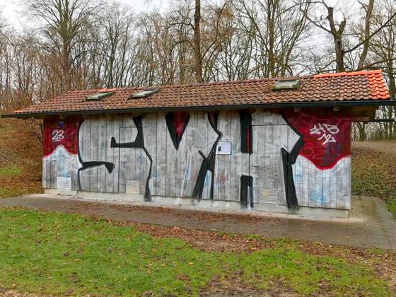 Vermutlich haben Fans des SV Heimstetten die Toilettenanlage am Heimstettener See mit einem Graffiti verziert. Foto: Polizei München
