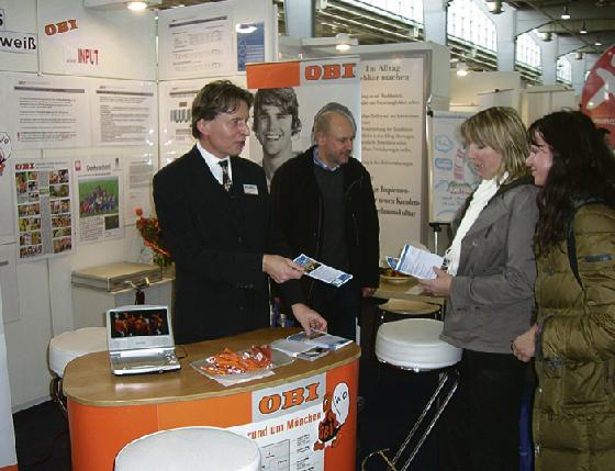 Werner Wengert (li.), Leiter Personalmanagement und -entwicklung, informiert Besucher am OBI-Messestand.	
