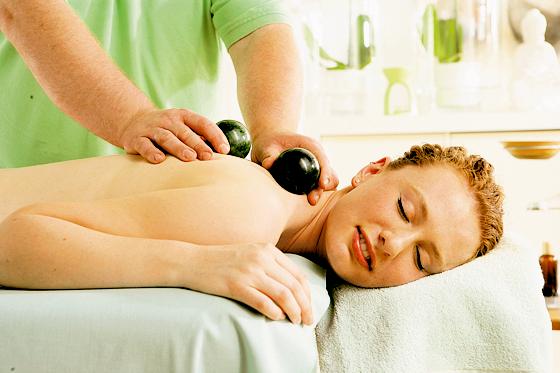 Die Kombination aus warmer Ölmassage und Rollen von Edelstein­kugeln auf dem Körper bewirkt bei der Aurum-Manus-Massage eine wohltuende Entspannung.