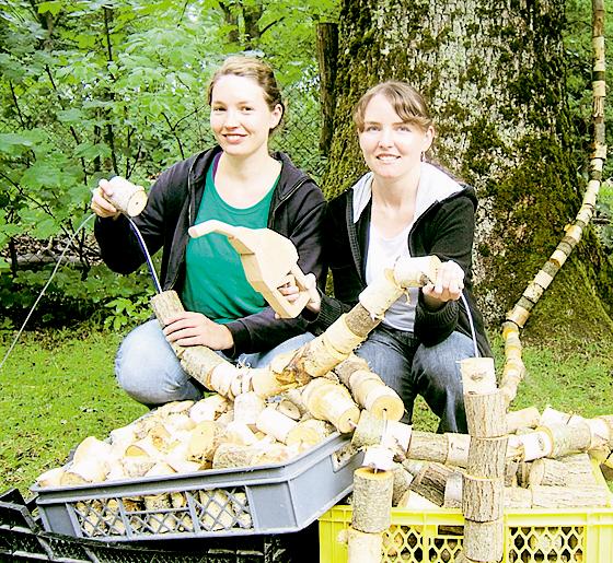 Die Holzbildhauerinnen Lisa Mayer und Julia Priss beim Aufbau des Kunstwerks »Aufgetankt«, eine hölzerne Zapfsäule mit Schlauch, die symbolisch einen Baum anzapft.  Foto: Veranstalter