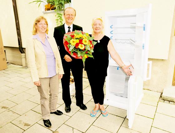 Ruth Waldmann, Prokuristin der AWO, und Dr. Kurt Mühlhäuser, Vorsitzender der SWM-Geschäftsführung, übergeben Regina H. einen Kühlschrank. Foto: SWM
