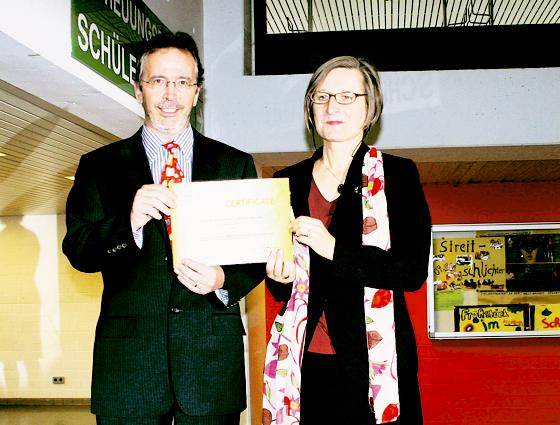 Volker Hörold, Bundeskoordinator der UNESCO-Projektschulen, übergibt Schulleiterin Cornelia Folger die Anerkennungsurkunde. 	Foto: mka