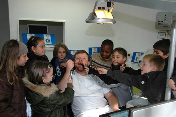 Rollentausch: Der Zahnarzt als Patient, die Schüler als Zahnärzte: Christian Gleau wird von den Kindern genau untersucht. Foto: KZVB