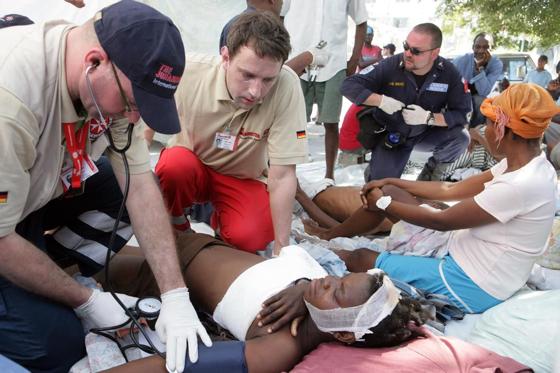 Der Münchner Arzt Dr. Adrian Roth (2.v.li.) untersucht mit seinen Kollegen eine Patientin auf der Straße vor einem überfüllten Krankenhaus in Port-au-Prince. Foto: Birgit Betzelt/Johanniter