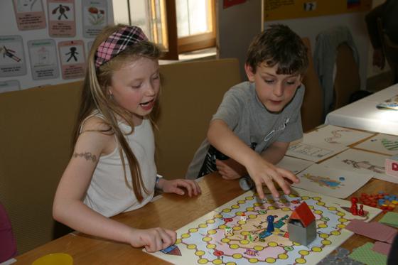 Zwei Kinder vom Kinderhaus Harthof erklären ihr Spiel „Das ist unfair!“, das den 1. Preis beim Ideenwettbewerb „Diskriminierung geht alle an“ gewonnen hat. Foto: KJR