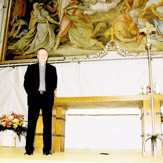 Findig hat Pfarrer Ulrich Babinsky den behelfsmäßigen Altar nach vorne verlegt: Die Folie mit dem Gemäldefoto verdeckt die dahinterliegenden Baugerüste. 	F.: ko